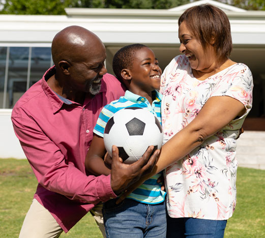 Grandparents smiling with grandson holding soccer ball
