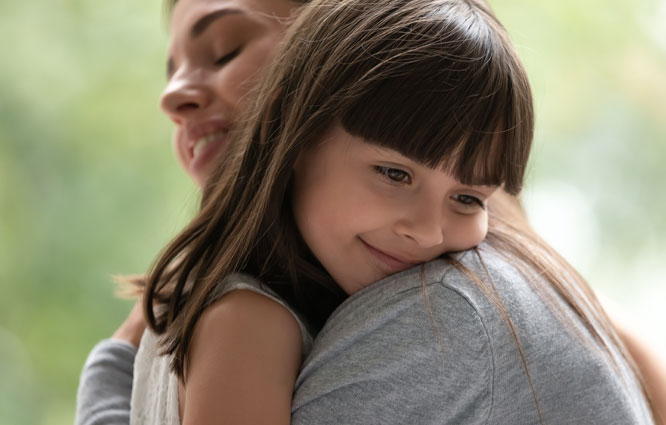 Young girl smiling and hugging woman